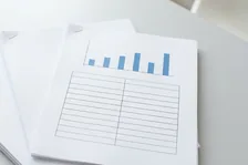 罫線だけの表と青い棒グラフを刷った資料が重なっているところ